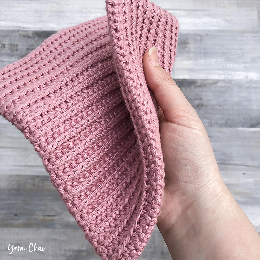 hand holding pink crochet washcloth