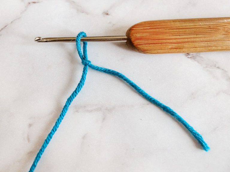 A blue yarn with a wooden handle and a crochet hook.