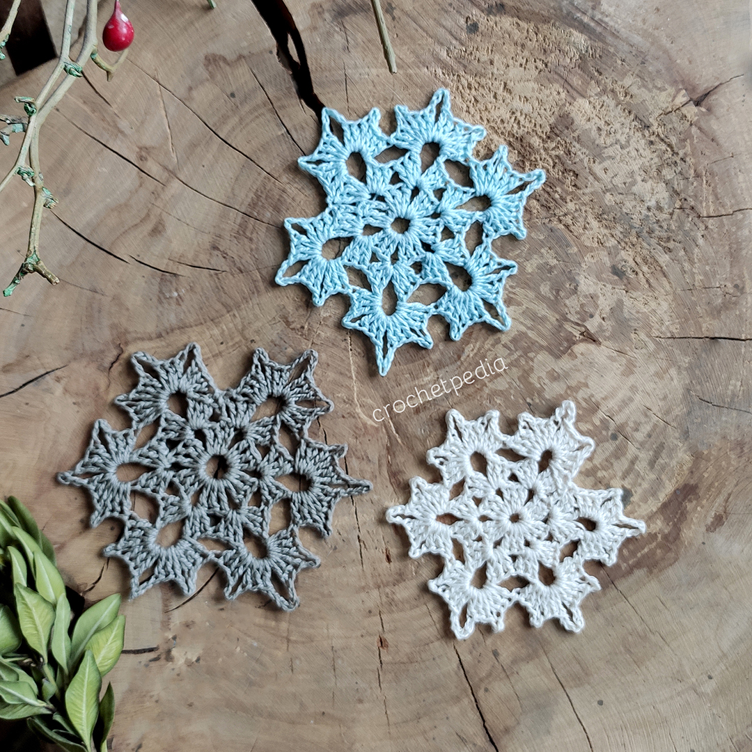 three snowflakes in different colors on wood