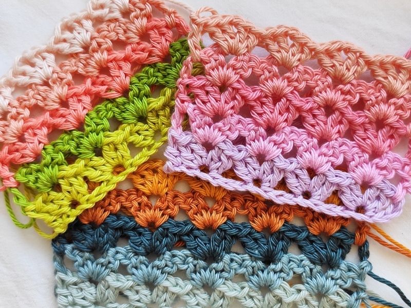 A group of colorful crochet stitches on a white surface.