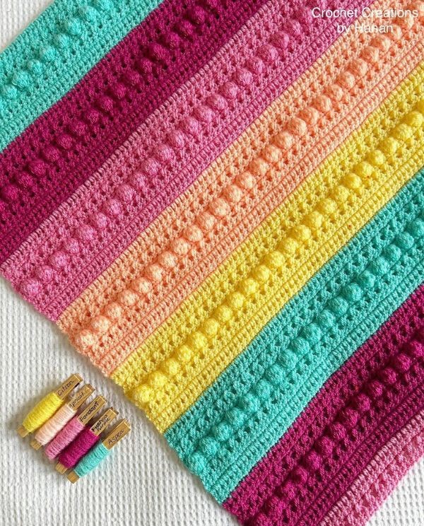 A crocheted afghan with colorful yarn and needles.