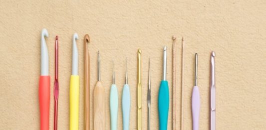 A set of crochet hooks on a beige background.