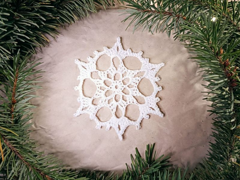 A white snowflake surrounded by pine branches.