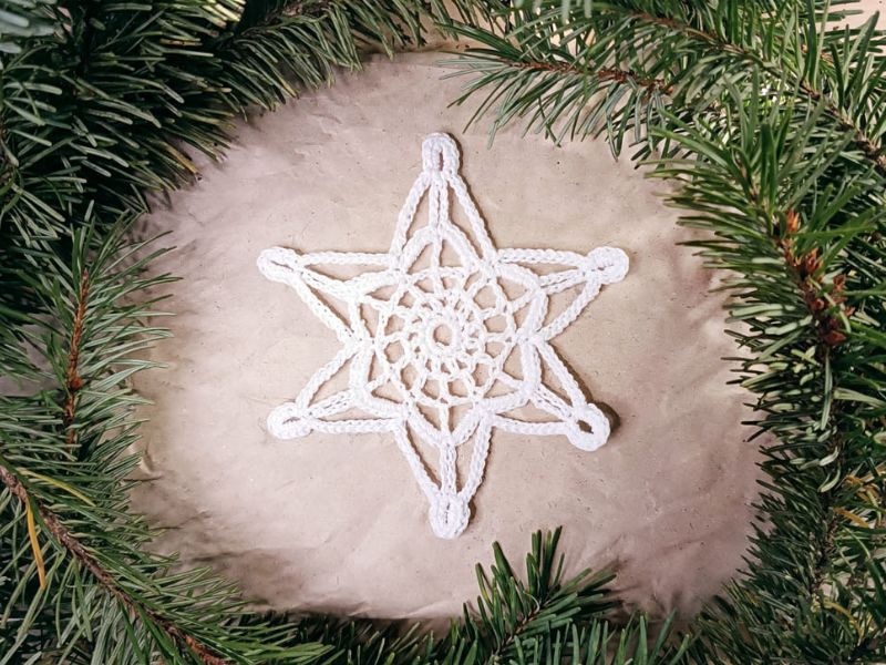 A white star shaped ornament on a christmas tree.