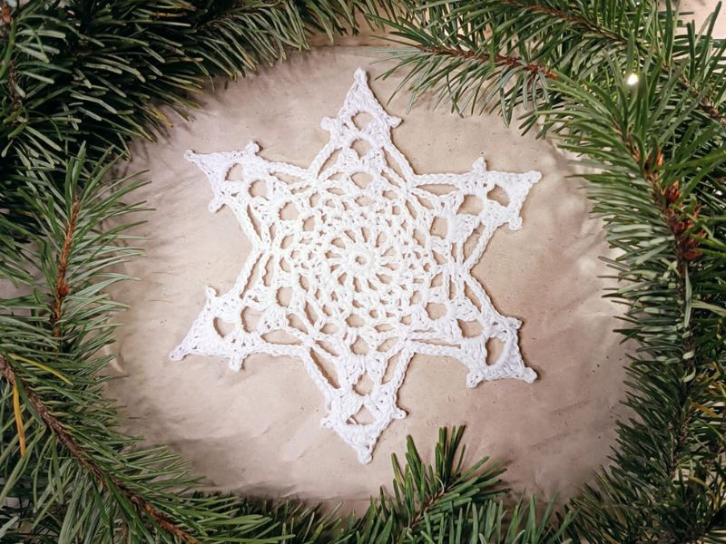 A white snowflake is hung in a christmas wreath.