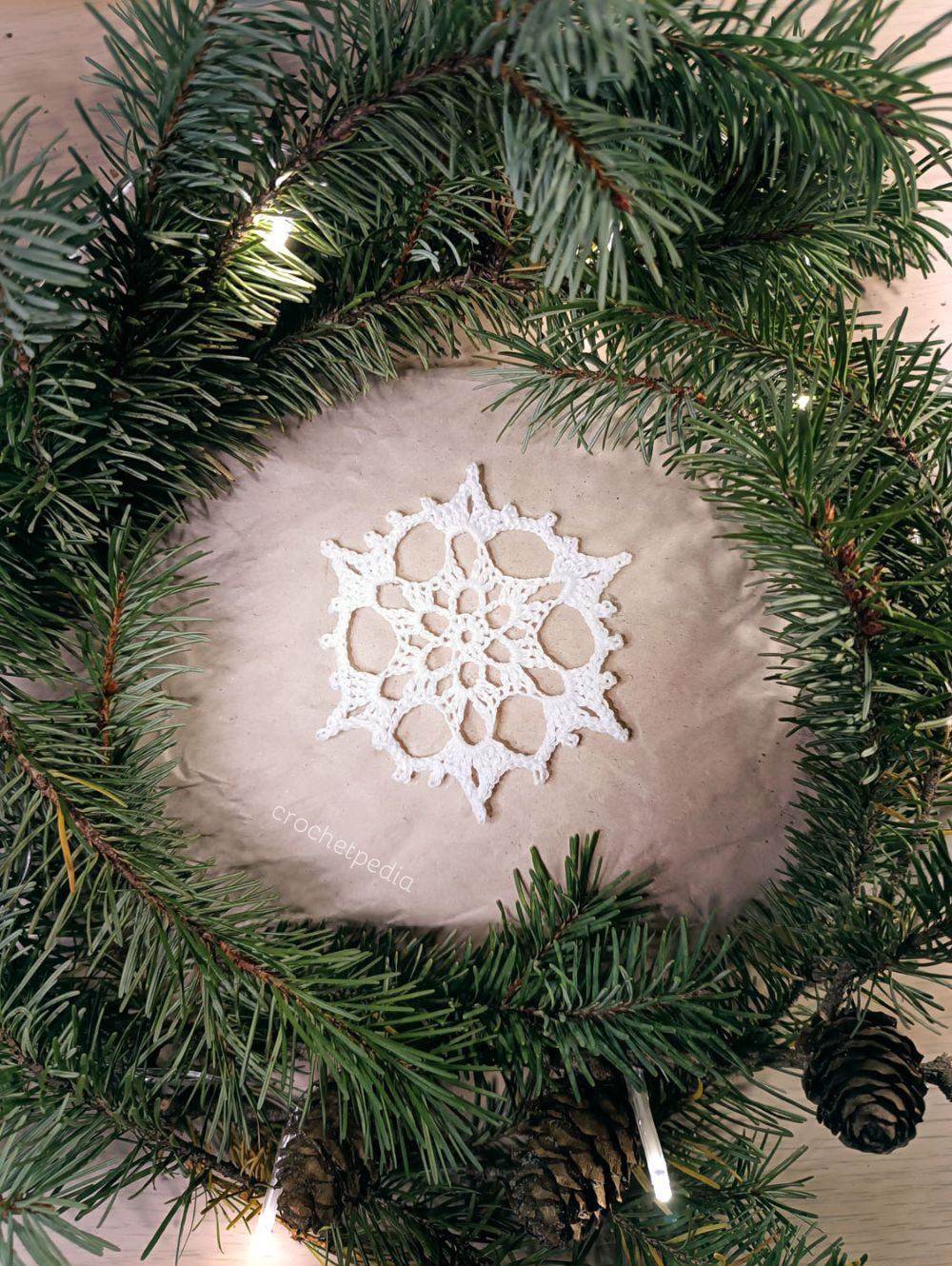 A white snowflake in the middle of a pine tree.
