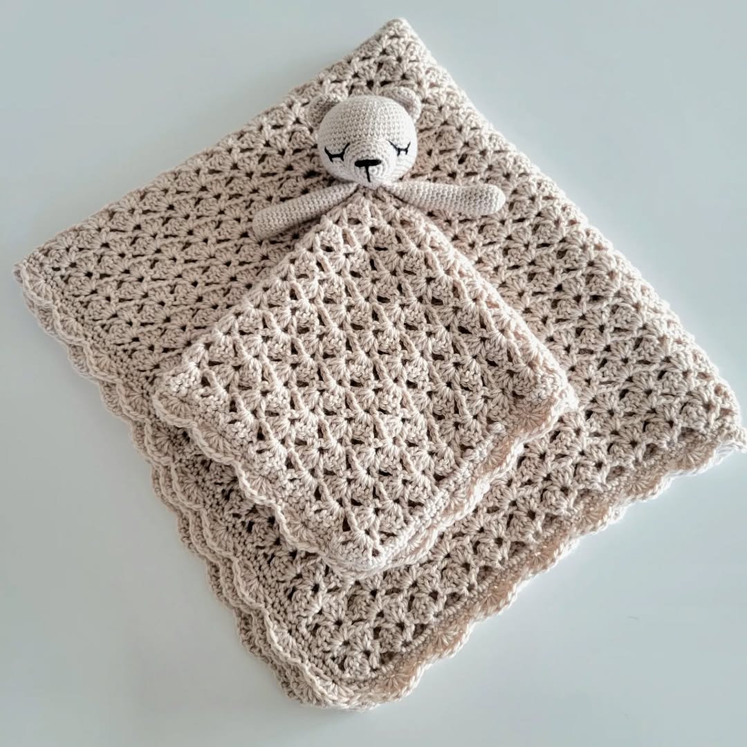 beige crochet baby blanket folded with matching toy on top